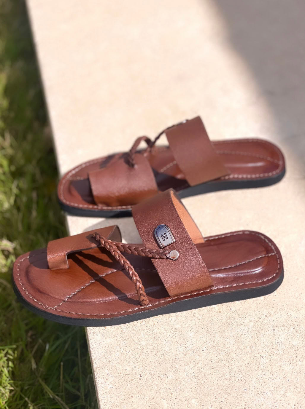 les sandales KIATEMA en cuir marron sont portées par un modèle, illustrant leur ajustement confortable et leur style élégant. La sangle tressée et la finition en cuir haut de gamme sont mises en valeur, démontrant l'artisanat sénégalais.
