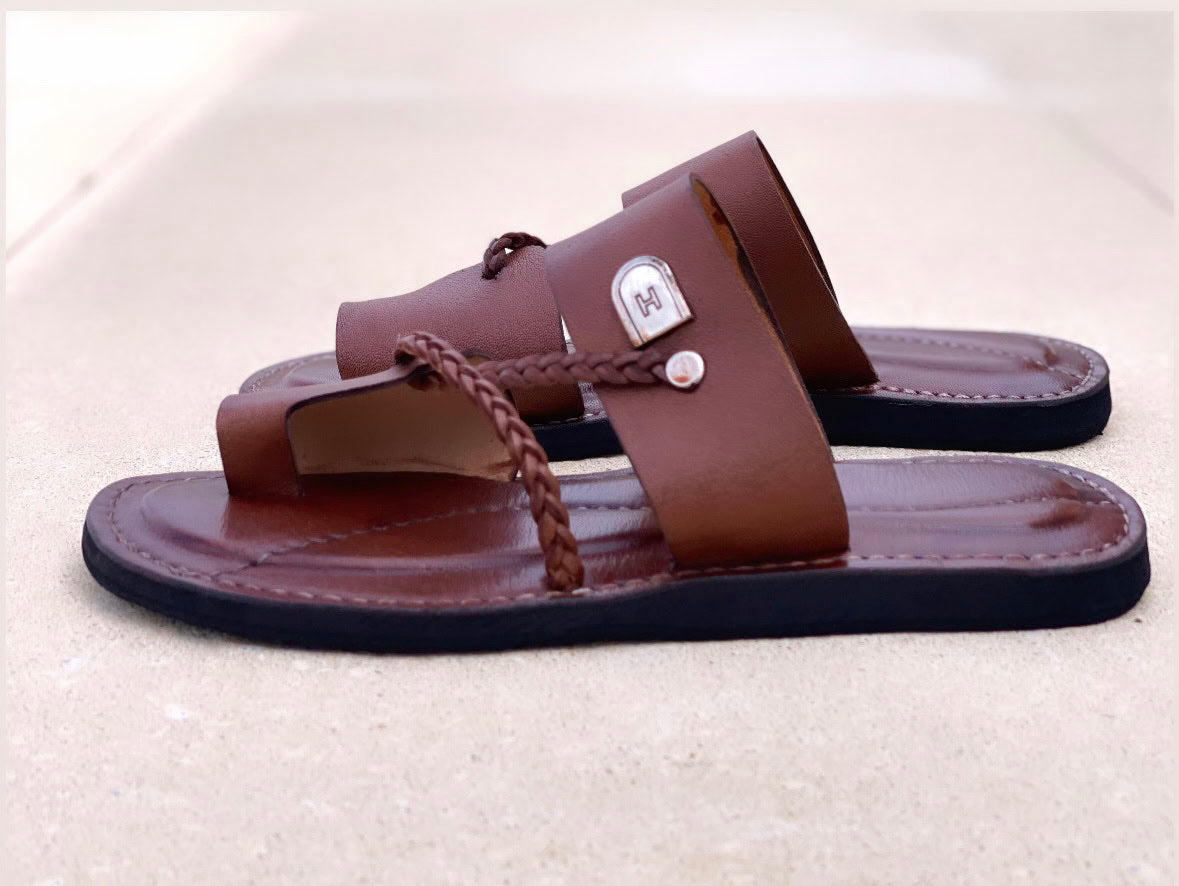 les sandales KIATEMA en cuir marron sont portées par un modèle, illustrant leur ajustement confortable et leur style élégant. La sangle tressée et la finition en cuir haut de gamme sont mises en valeur, démontrant l'artisanat sénégalais.