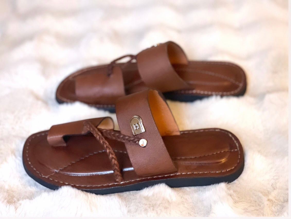 les sandales KIATEMA en cuir marron sont portées par un modèle, illustrant leur ajustement confortable et leur style élégant. La sangle tressée et la finition en cuir haut de gamme sont mises en valeur, démontrant l'artisanat sénégalais.