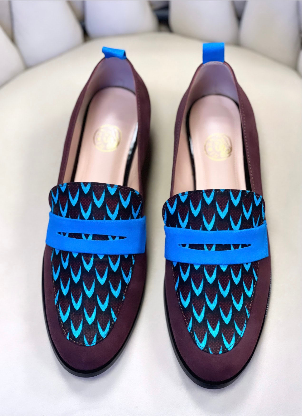 Ces mocassins faits main en cuir souple bordeaux et tissu ethnique africain bleu incarnent le mélange ultime de confort, d'élégance et d'authenticité. Chaque paire est unique, conçue pour ceux qui souhaitent allier style et culture. Que ce soit pour une journée décontractée ou une soirée spéciale, les mocassins SEULIE sont le choix idéal.