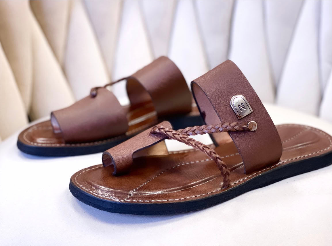 les sandales KIATEMA en cuir marron sont portées par un modèle, illustrant leur ajustement confortable et leur style élégant. La sangle tressée et la finition en cuir haut de gamme sont mises en valeur, démontrant l'artisanat sénégalais.
