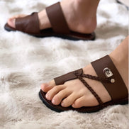 les sandales KIATEMA en cuir marron sont portées par un modèle, illustrant leur ajustement confortable et leur style élégant. La sangle tressée et la finition en cuir haut de gamme sont mises en valeur, démontrant l'artisanat sénégalais.