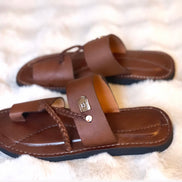 les sandales KIATEMA en cuir marron sont portées par un modèle, illustrant leur ajustement confortable et leur style élégant. La sangle tressée et la finition en cuir haut de gamme sont mises en valeur, démontrant l'artisanat sénégalais.