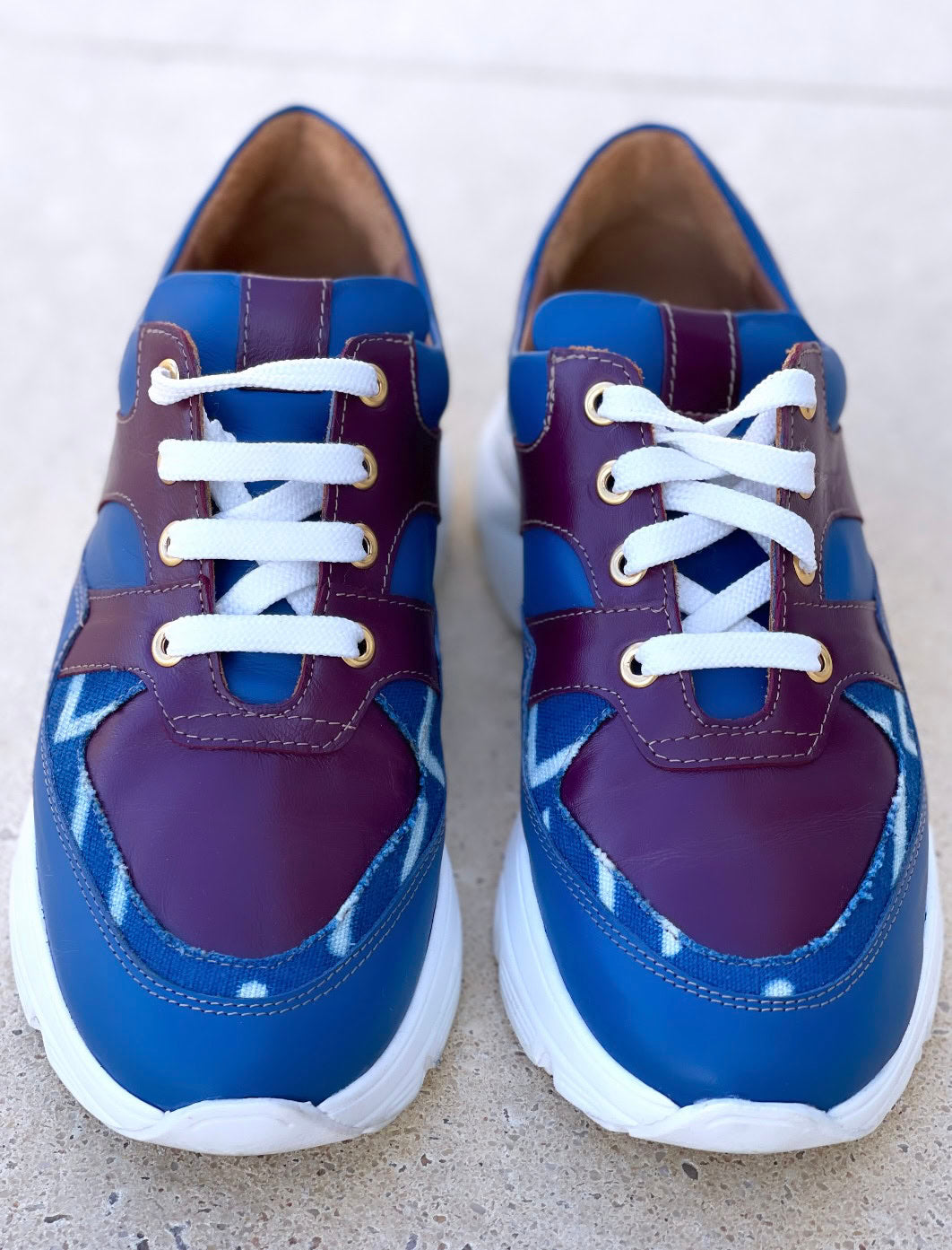 Caractéristiques: * Tige: En cuir véritable et tissu bogolan * Semelle intérieure: Confort orthopédique * Semelle extérieure: Caoutchouc robuste pour une adhérence optimale * Fermeture: Lacets en coton renforcé * Couleur: Mélange de bleu et bordeaux * Taille disponible: Du 36 au 45 Avantages: * Confort: Conception ergonomique pour un usage quotidien * Durabilité: Matériaux de haute qualité pour une longue durée de vie * Style: Design contemporain avec une touche culturelle unique * Polyvalence: Idéales pour