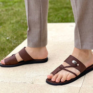 les sandales KIATEMA en cuir marron sont portées par un modèle, illustrant leur ajustement confortable et leur style élégant. La sangle tressée et la finition en cuir haut de gamme sont mises en valeur, démontrant l'artisanat sénégalais.
