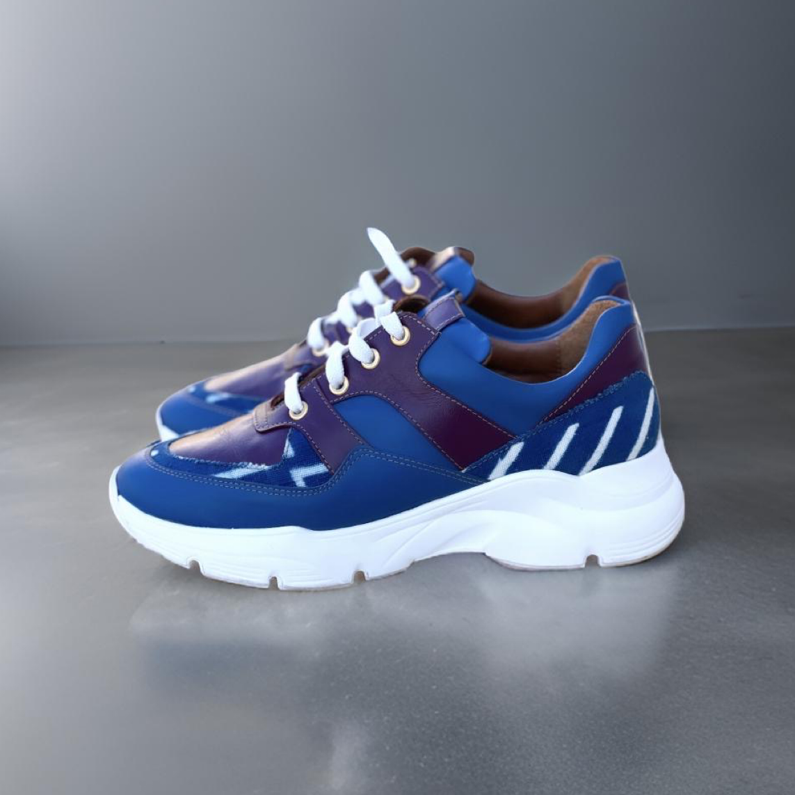 Caractéristiques: * Tige: En cuir véritable et tissu bogolan * Semelle intérieure: Confort orthopédique * Semelle extérieure: Caoutchouc robuste pour une adhérence optimale * Fermeture: Lacets en coton renforcé * Couleur: Mélange de bleu et bordeaux * Taille disponible: Du 36 au 45 Avantages: * Confort: Conception ergonomique pour un usage quotidien * Durabilité: Matériaux de haute qualité pour une longue durée de vie * Style: Design contemporain avec une touche culturelle unique * Polyvalence: Idéales pour